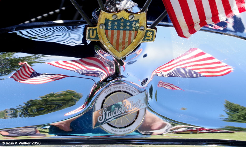 Reflected flags on the hood ornament of a restored Studebaker President sedan