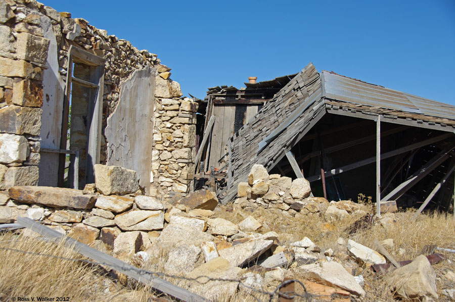 A stone building and a wooden shed collapse together at Tuscarora, Nevada