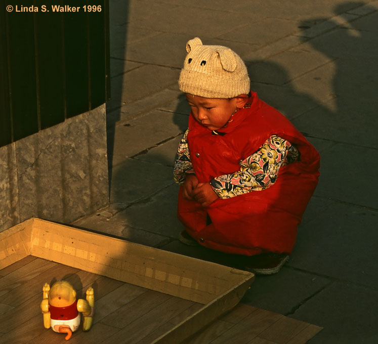 Child fascinated by a toy, Temple Of Heaven, Beijing, China