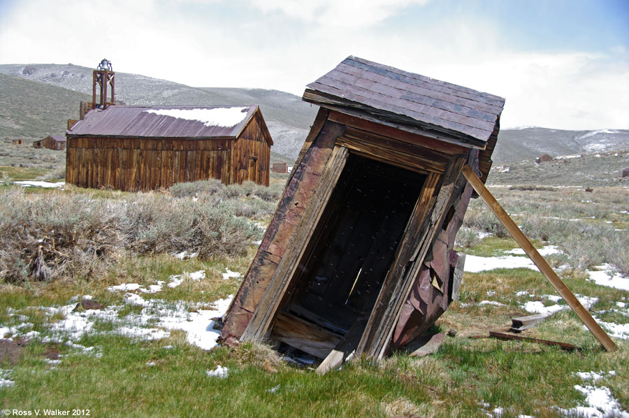 An old outhouse with tin can siding  leans at Bodie ghost town, California.