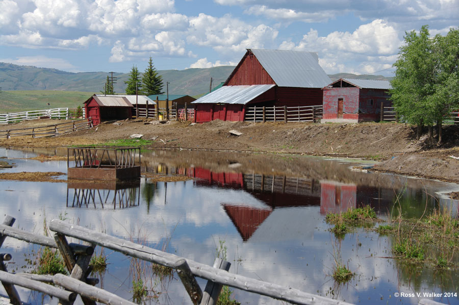 A snowmelt pond reflects the barns of a farm in Dingle, Idaho