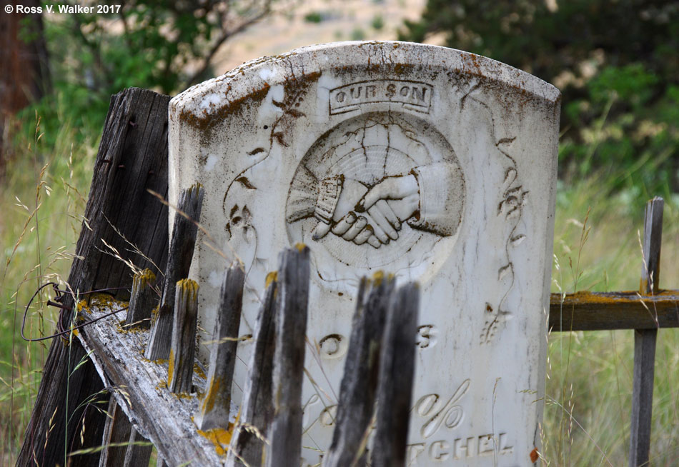 An ancient cemetery crib collapses against a headstone in Richmond, Oregon