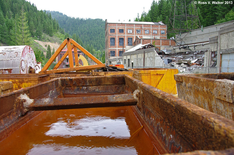 Ore bins with rusty water outside the mill buildings, Burke, Idaho