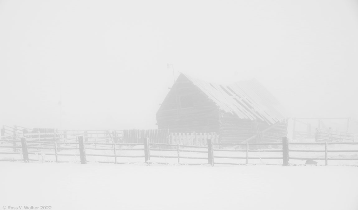 An old log barn can barely be seen through winter fog in Paris, Idaho